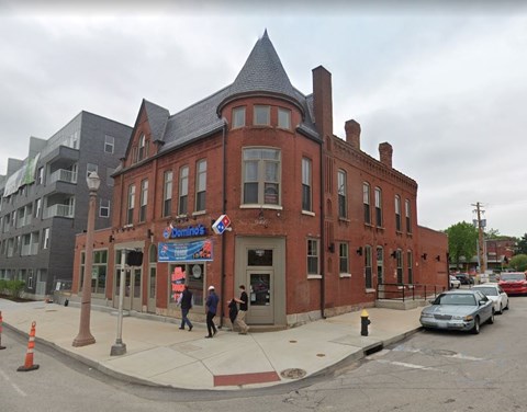 A red brick building with a blue sign that says "Dominos" in front of it.