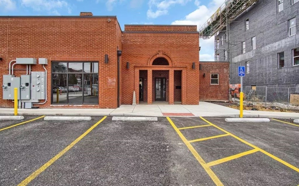the front of a brick building with a parking lot