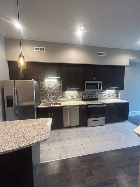 A kitchen with a granite counter top and stainless steel appliances.