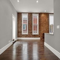 A room with a brick wall and wooden floors.