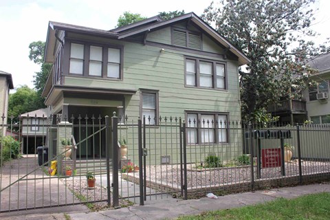 a green house with a fence and a gate in front of it
