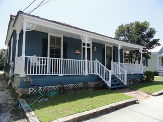 a blue house with a porch and a white railing