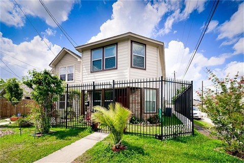a house with a yard and a fence in front of it