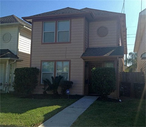 a tan house with a sidewalk in front of it