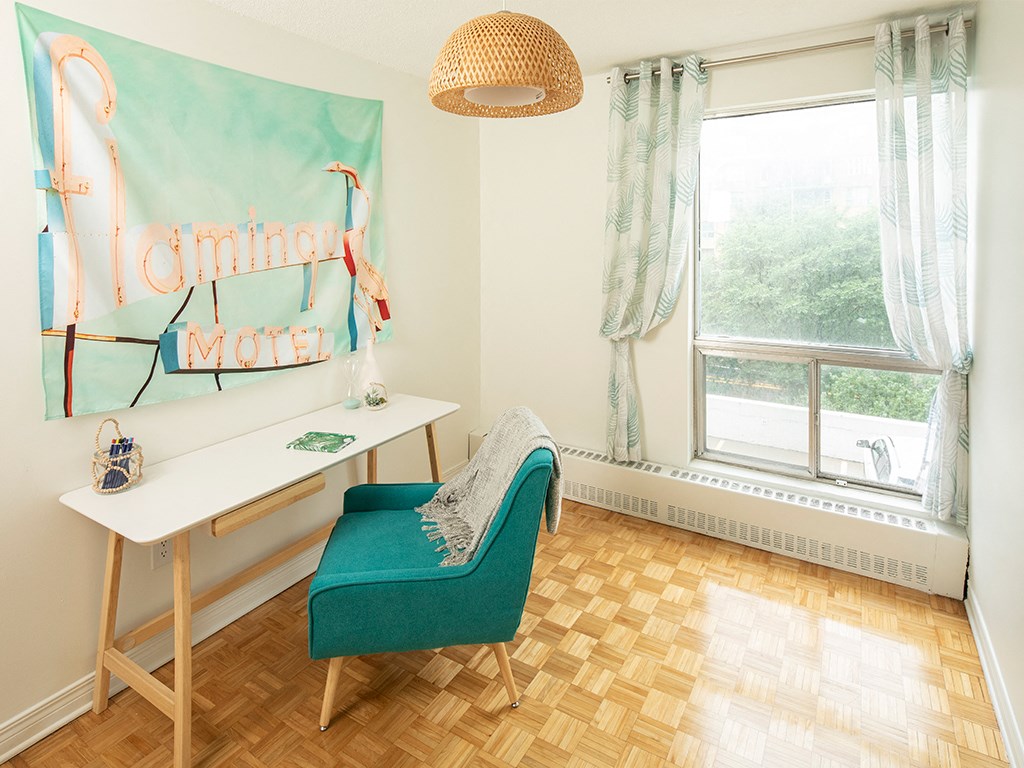 a home office with a green chair and a desk and a window