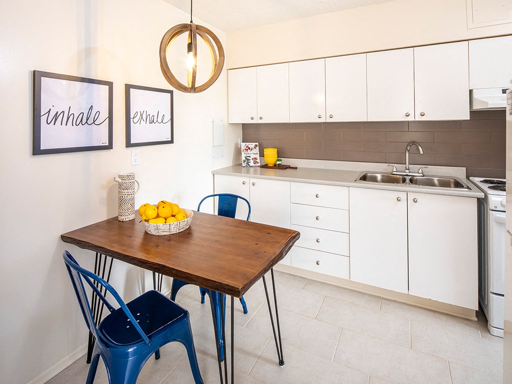 a kitchen with white cabinets and a table with blue chairs