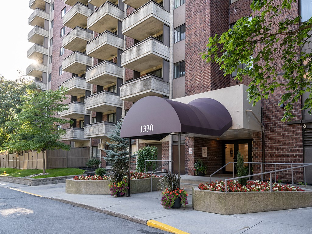 an apartment building with a black awning and a sidewalk