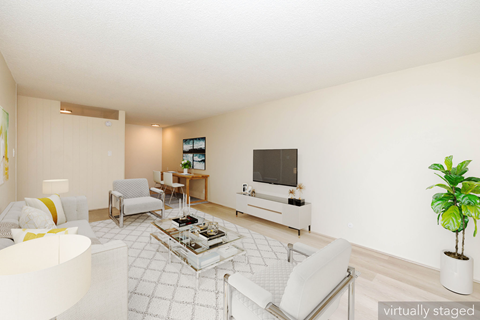 A living room with a white couch, a coffee table, and a television.