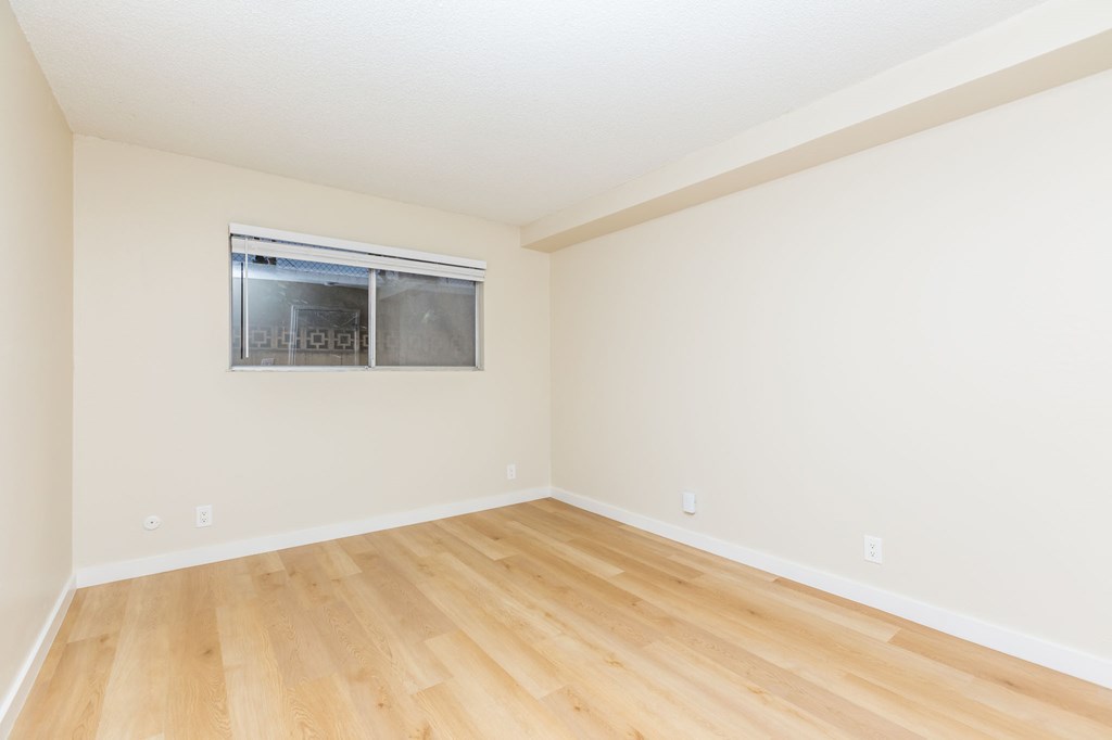 A room with a window and wooden flooring.