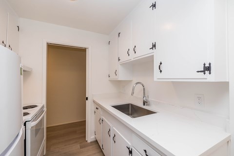 A kitchen with white cabinets and a white fridge.