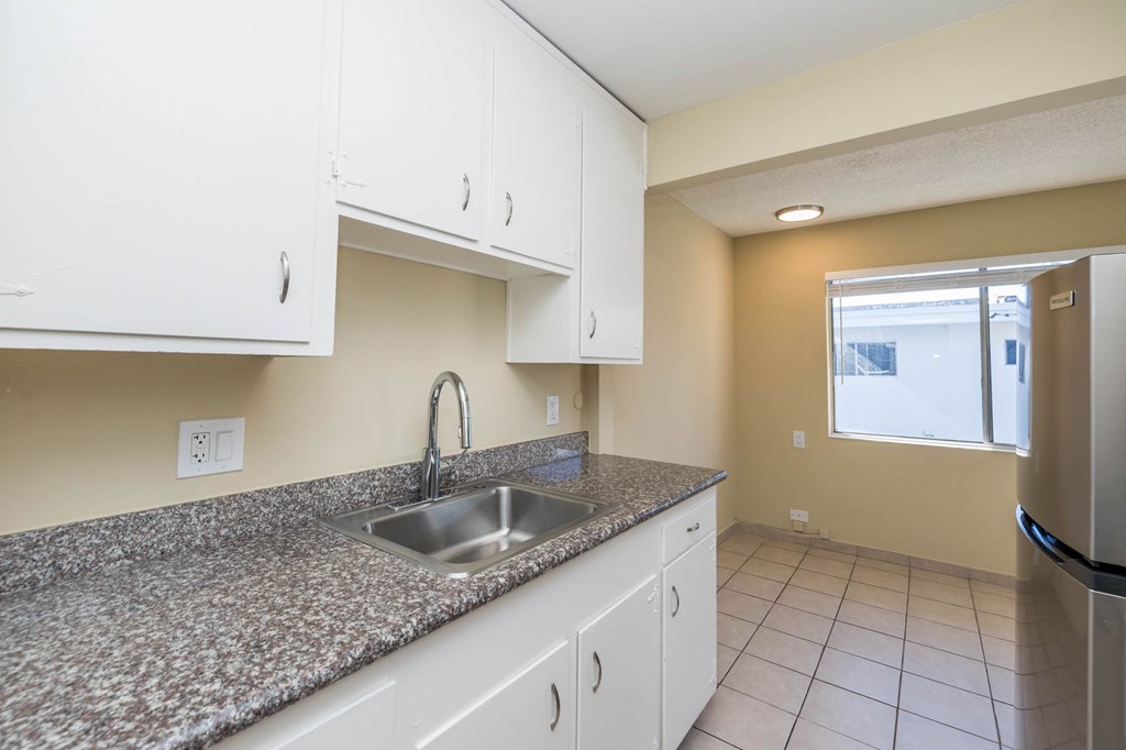 A kitchen with granite countertops and white cabinets.