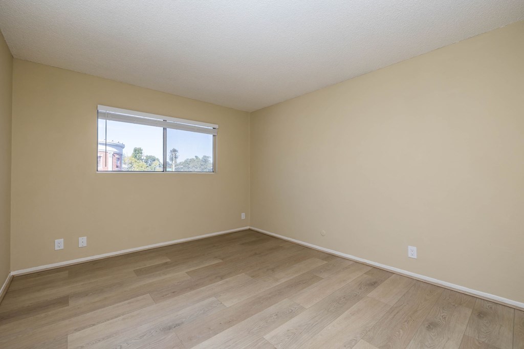 A room with a window and wooden flooring.