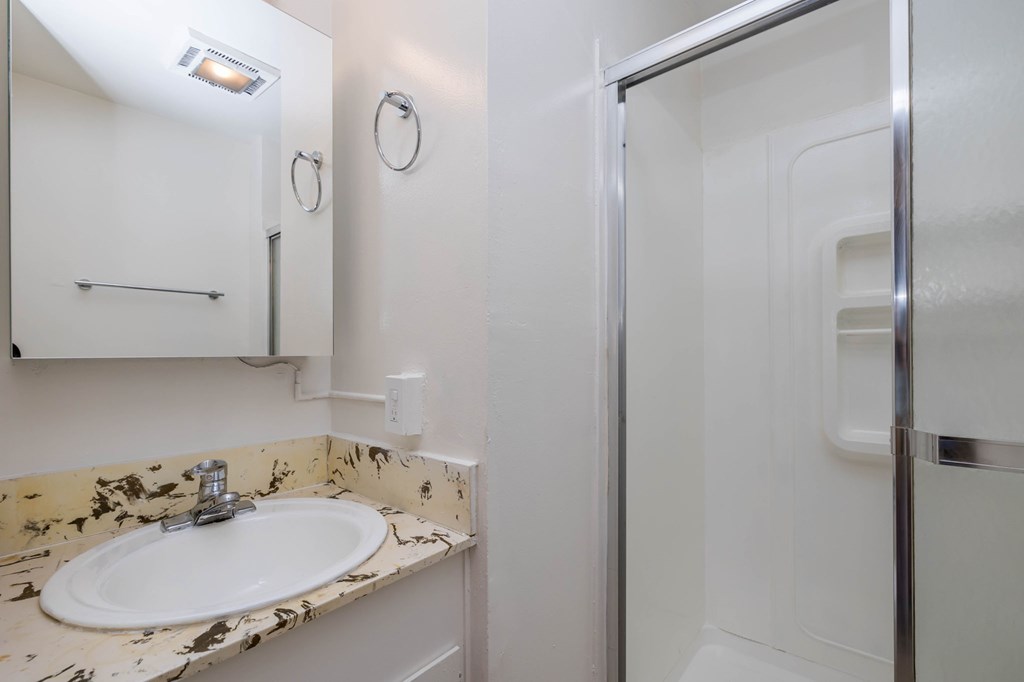 A white sink in a bathroom with a marbled counter top.