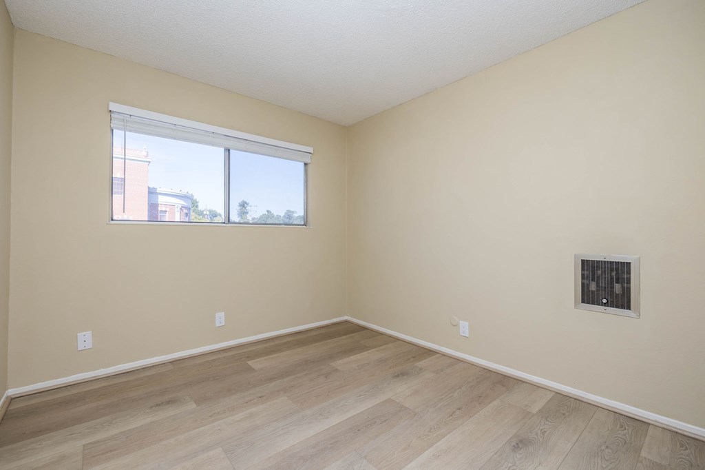 A room with a window and a vent on the wall.