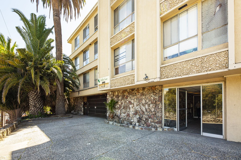 A building with a stone wall and a palm tree in front.