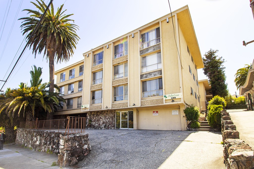 A yellow building with a stone wall in front.