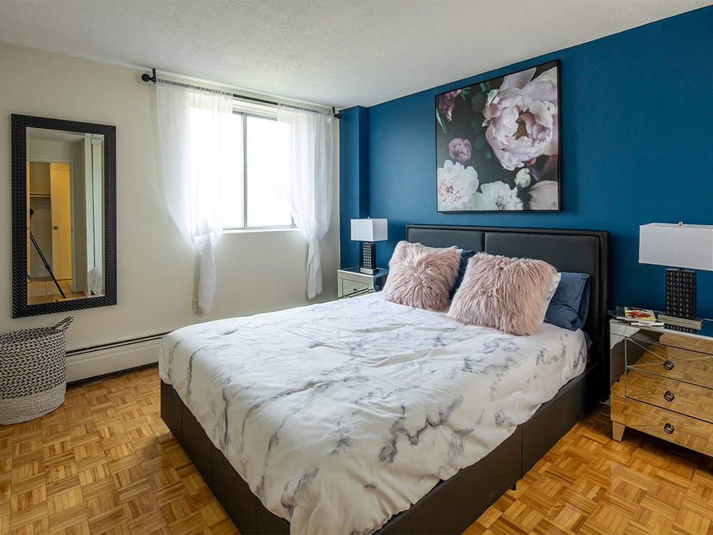 a bedroom with blue walls and a bed with a white comforter