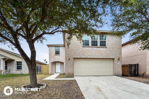 a large brick house with a garage door and a tree