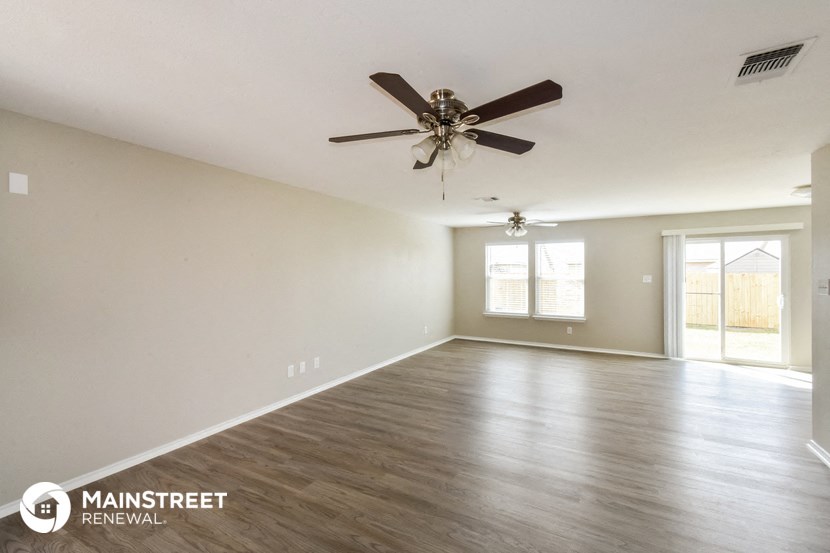 the spacious living room with ceiling fan and wood flooring