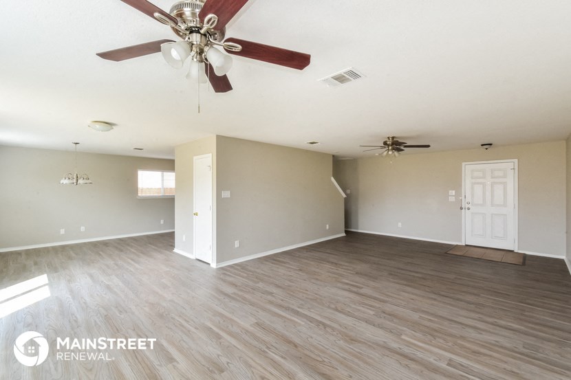 the living room of an empty house with a ceiling fan