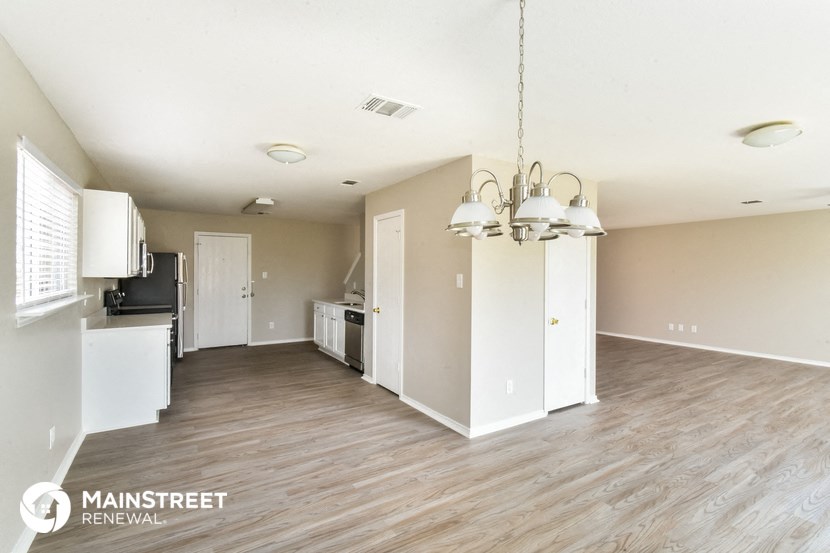 the living room and kitchen of an apartment with wood flooring