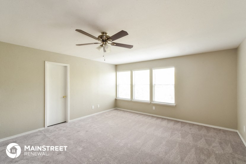 the spacious living room with ceiling fan and carpet