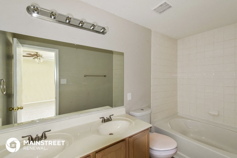 a bathroom with a sink and a mirror and a tub and a toilet