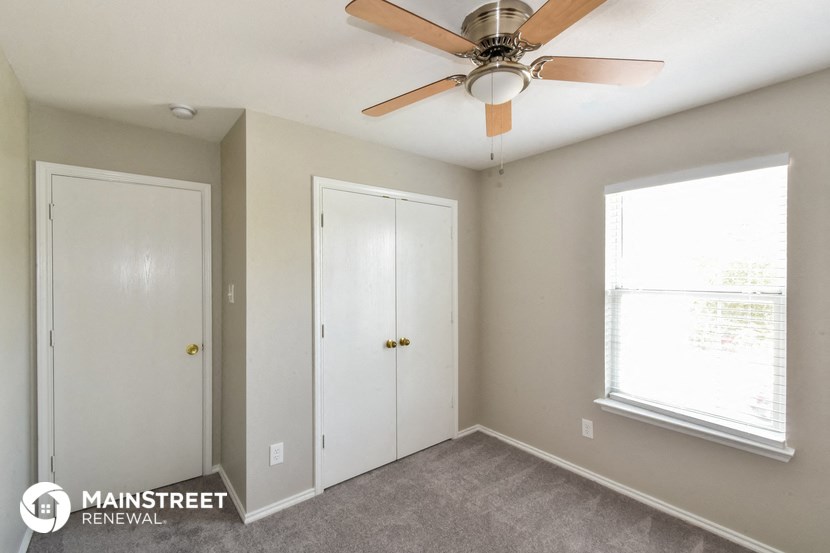 a bedroom with a ceiling fan and two doors