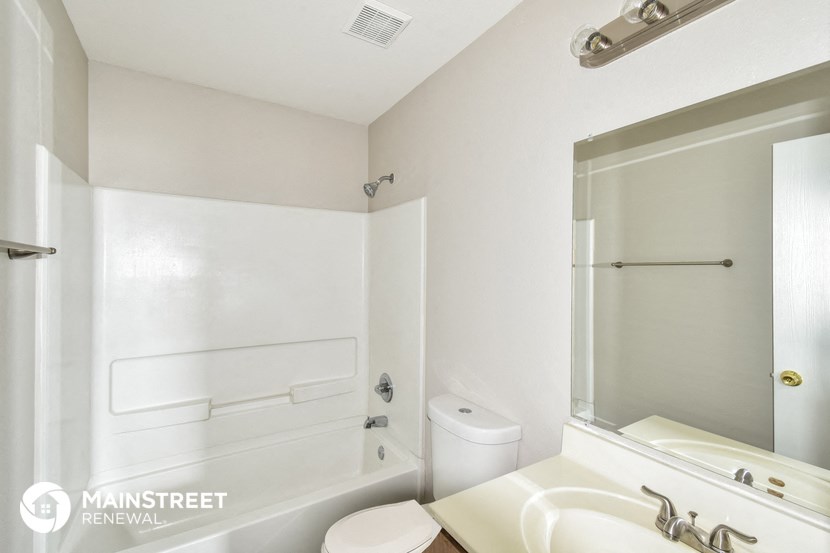 a white bathroom with a sink and a tub and a mirror
