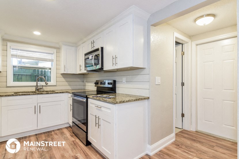 a kitchen with white cabinets and a stove and a microwave