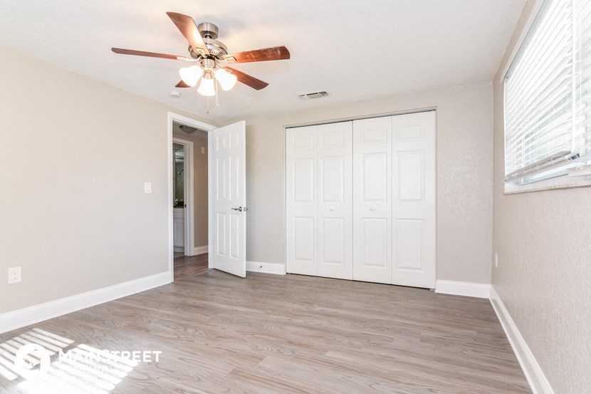 a living room with a ceiling fan and a door to a closet