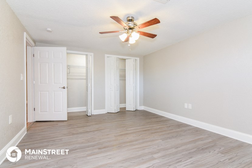 an empty living room with a ceiling fan and a closet