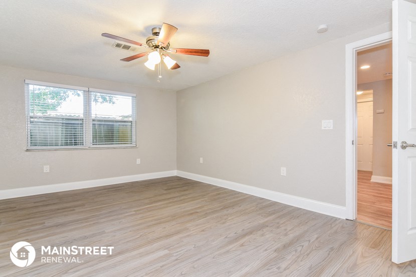 an empty living room with a ceiling fan and a window