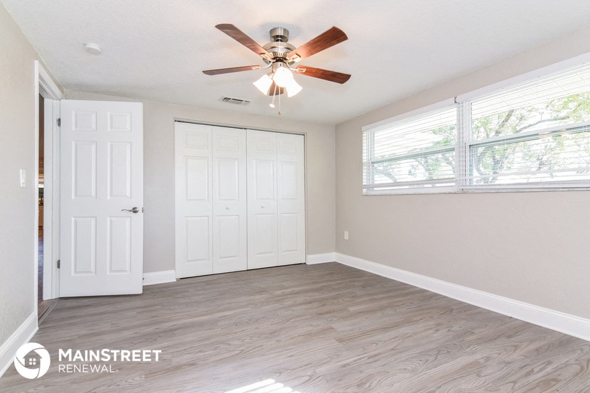 an empty living room with a ceiling fan and a window