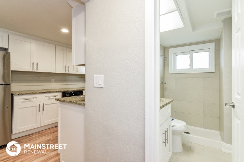 a white kitchen with white cabinets and a toilet and a sink