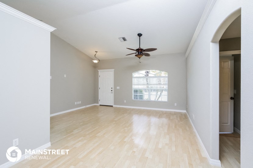 the living room and dining room with hardwood floors and a ceiling fan