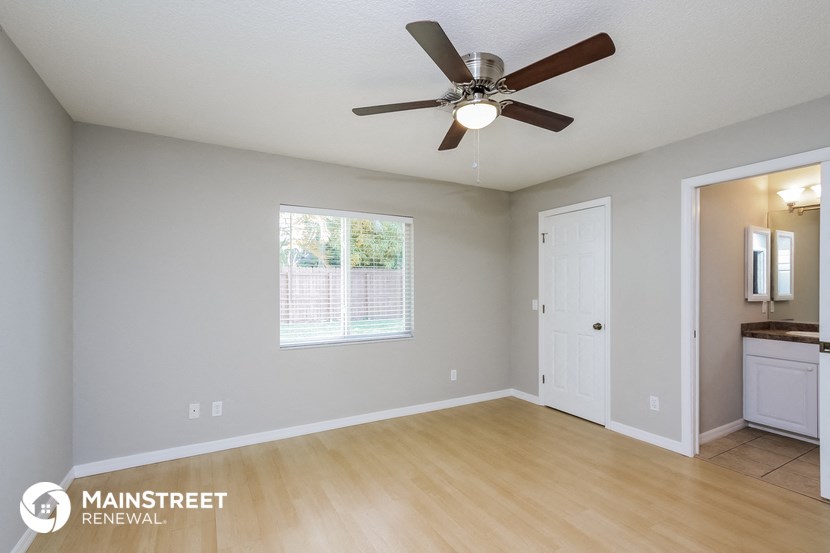 the living room is spacious and clean with a ceiling fan