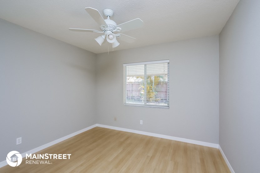 the spacious living room with a ceiling fan and wood flooring