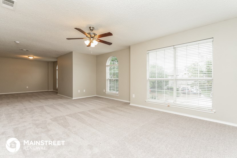 an empty living room with a ceiling fan and a large window