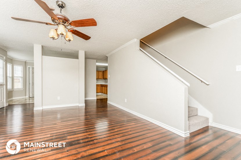 the living room and dining room with hardwood floors and a ceiling fan