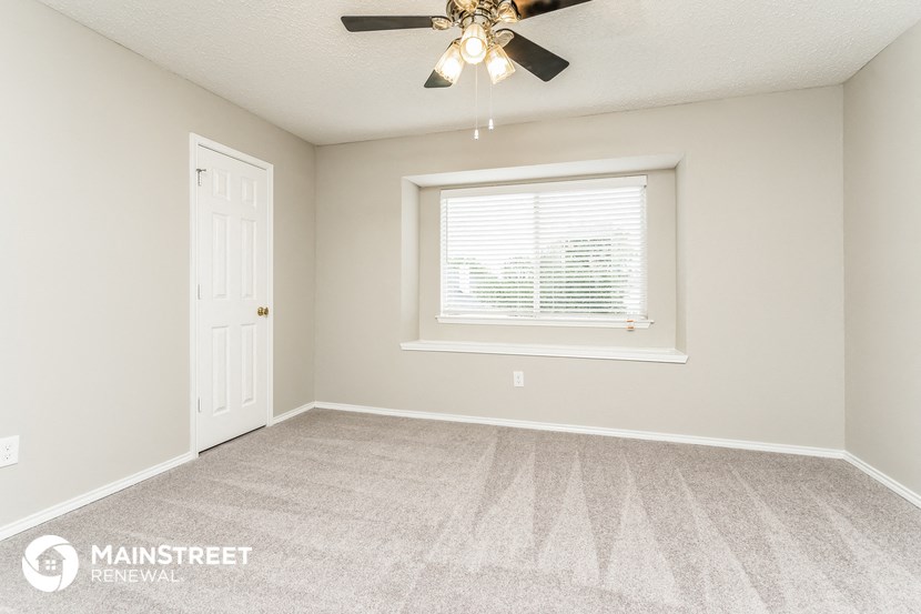 the bedroom of this manufactured home has a carpeted floor and a ceiling fan