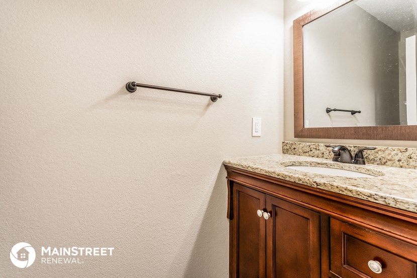 the master bathroom has a vanity and a large mirror