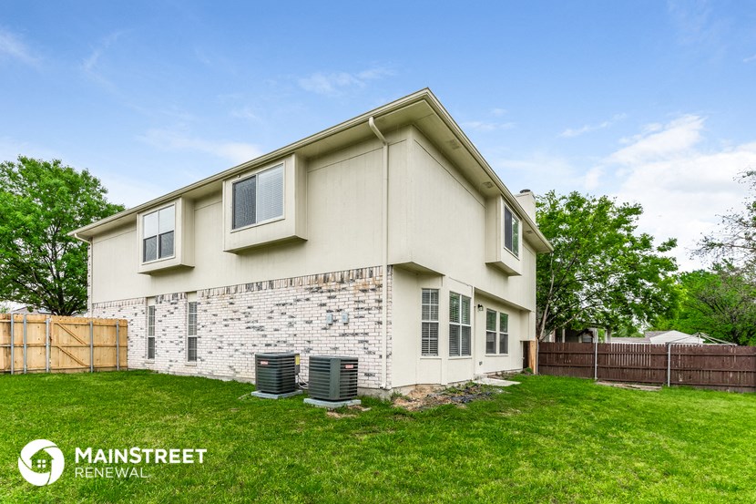 the exterior of a house with a lawn and a fence