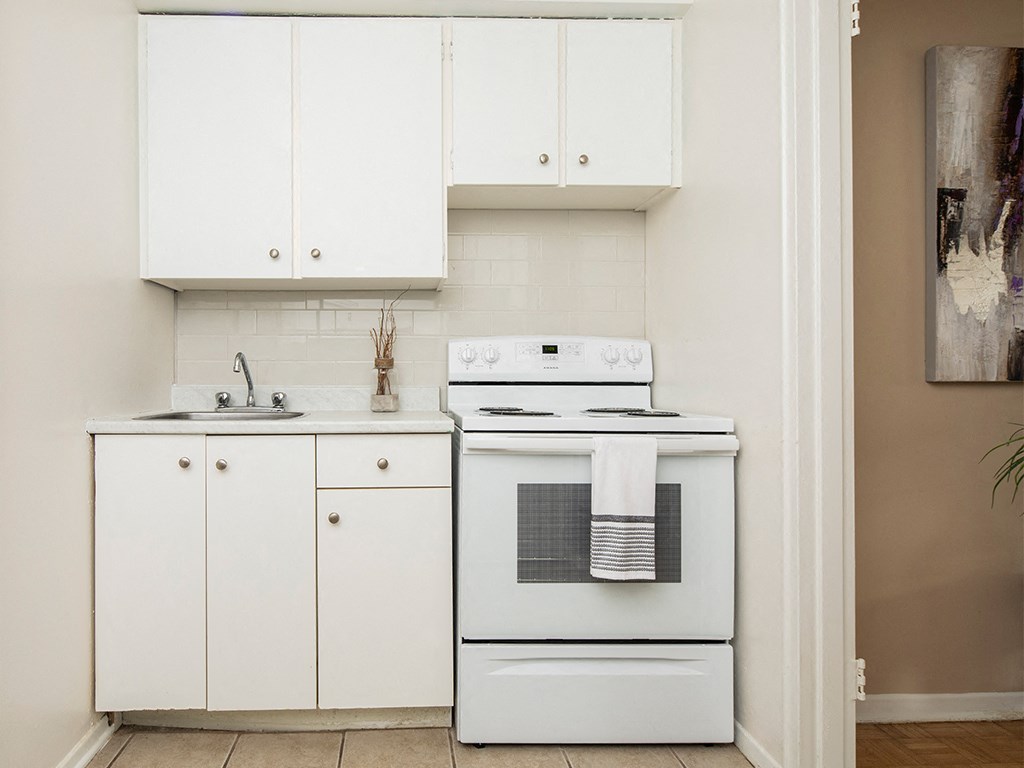 a kitchen with a stove and sink and white cabinets