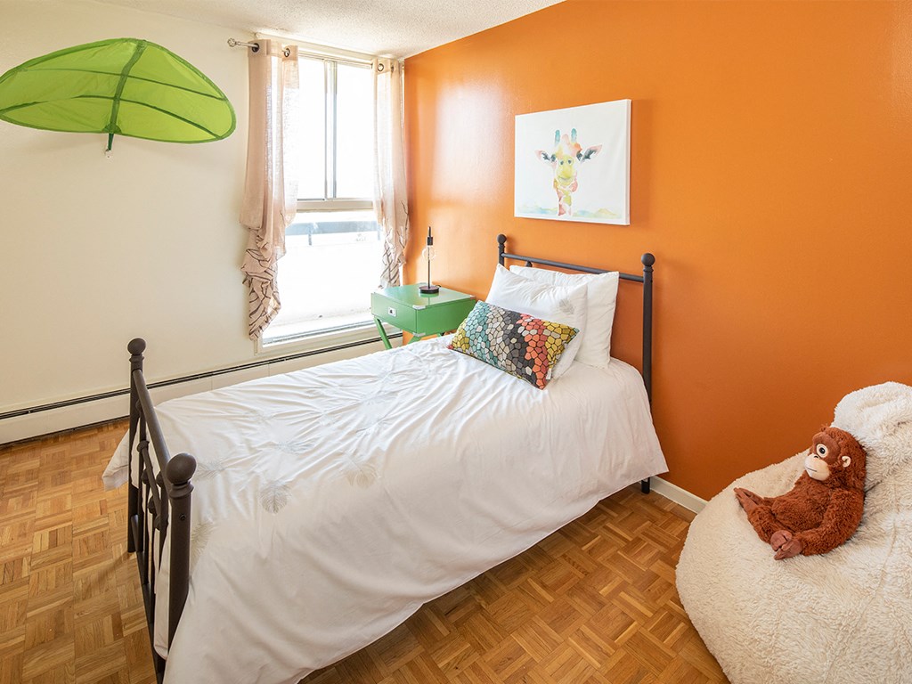 a bedroom with an orange wall and a bed with a white