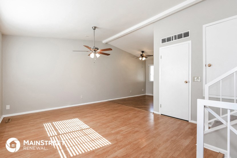 the living room and dining room with wood floors and a ceiling fan
