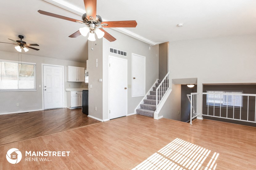 an empty living room with a ceiling fan and a staircase
