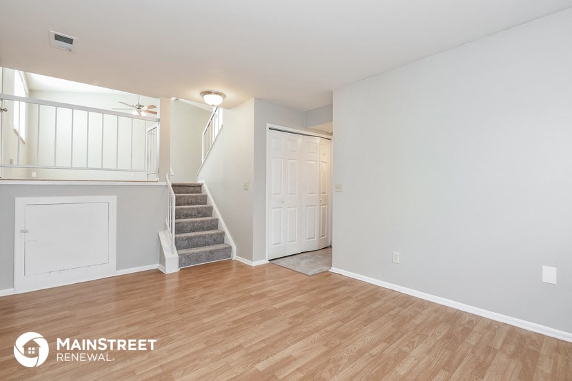 the living room and entryway of a white house with wood flooring