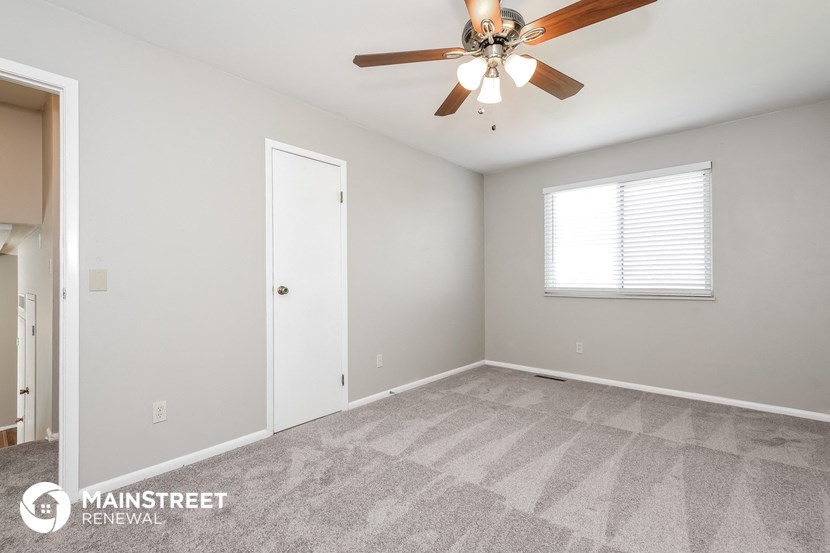 the spacious living room with ceiling fan and carpeting