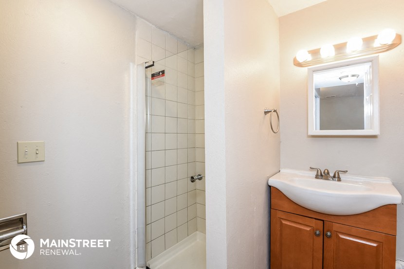 a bathroom with a sink and a shower and a mirror